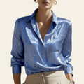 Person wearing a blue patterned shirt with a blurred background