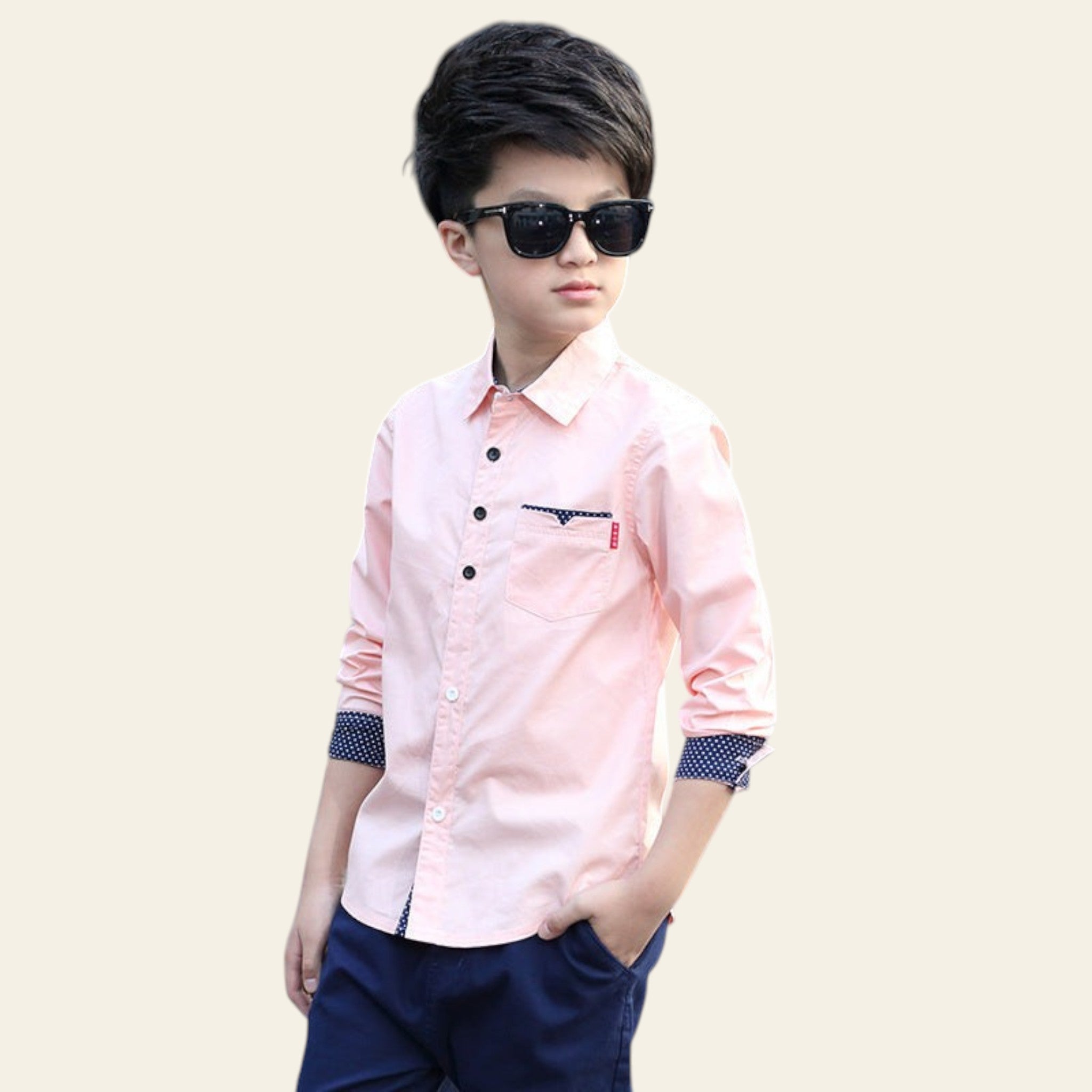 Child wearing a pink shirt with a logo and dark sunglasses on a street.