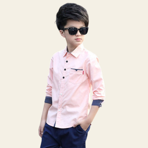 Child wearing a pink shirt with a logo and dark sunglasses on a street.
