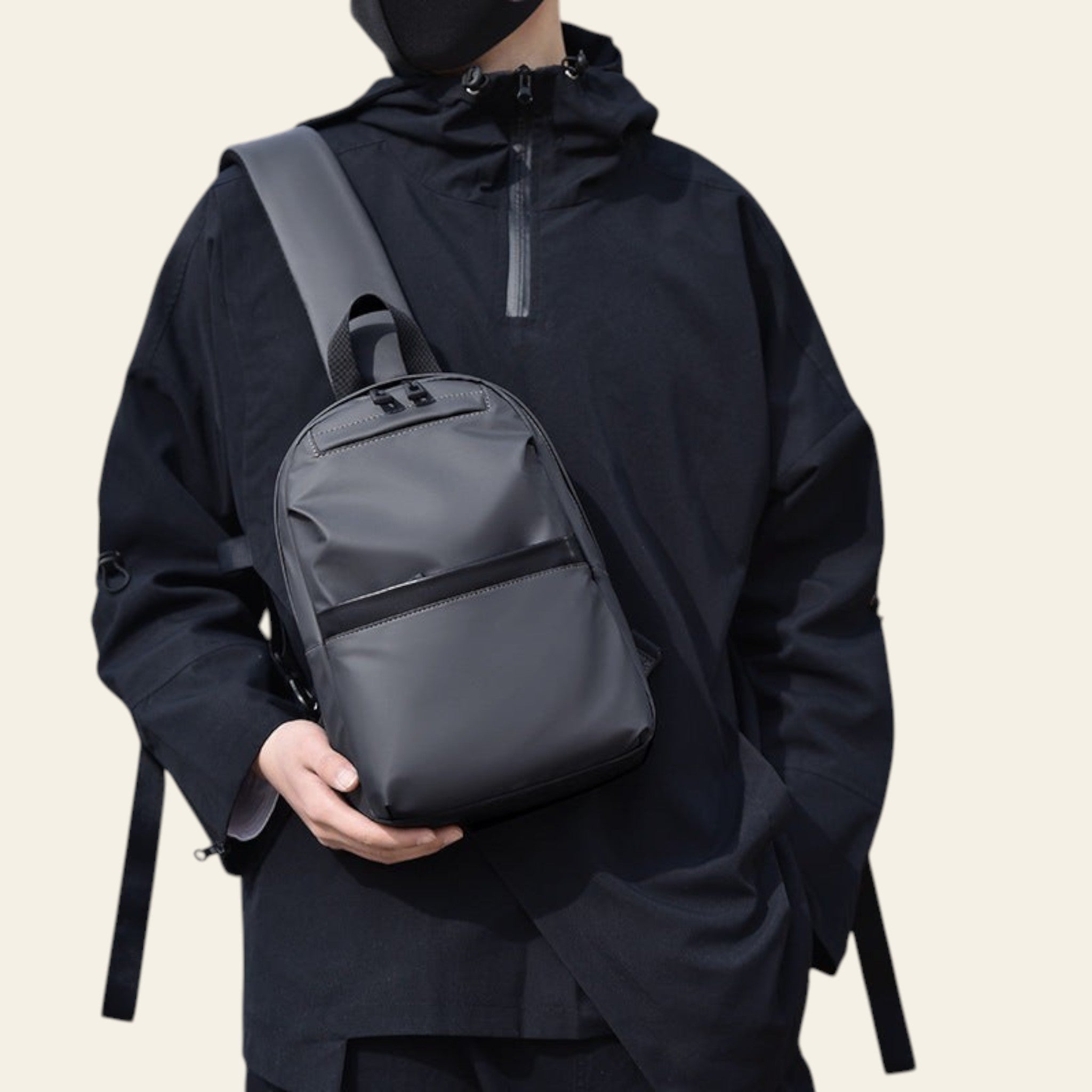 Person wearing a dark jacket holding a gray backpack against a blurred background