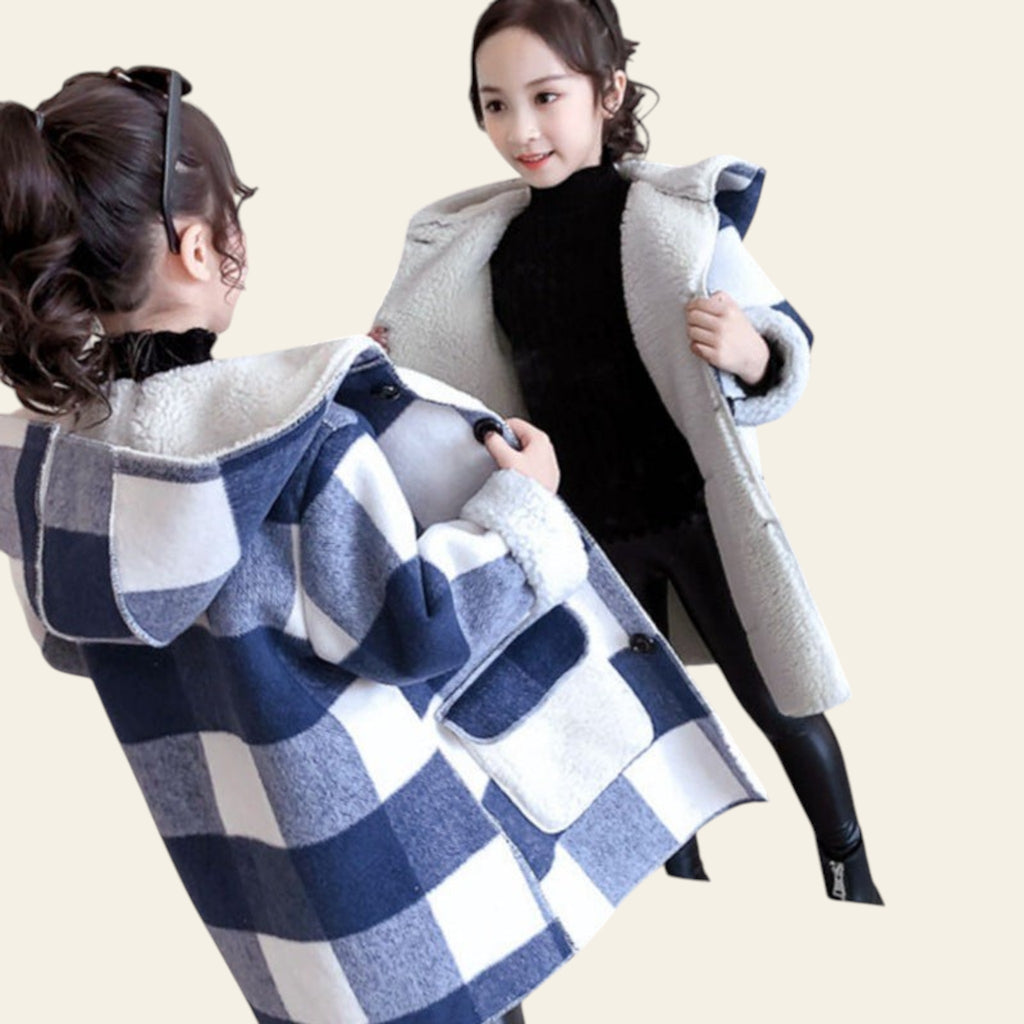 Woman trying on a blue and white checkered coat in front of a mirror.