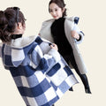Woman trying on a blue and white checkered coat in front of a mirror.
