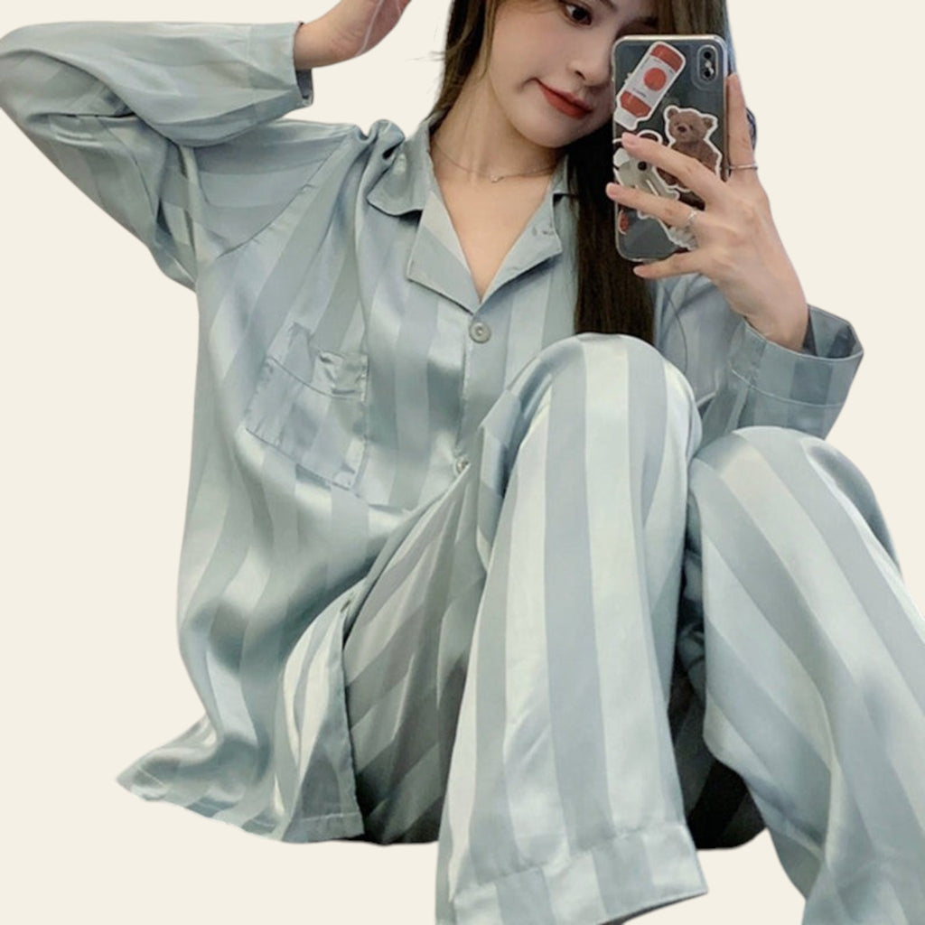 Woman in light blue pajama set taking a mirror selfie.