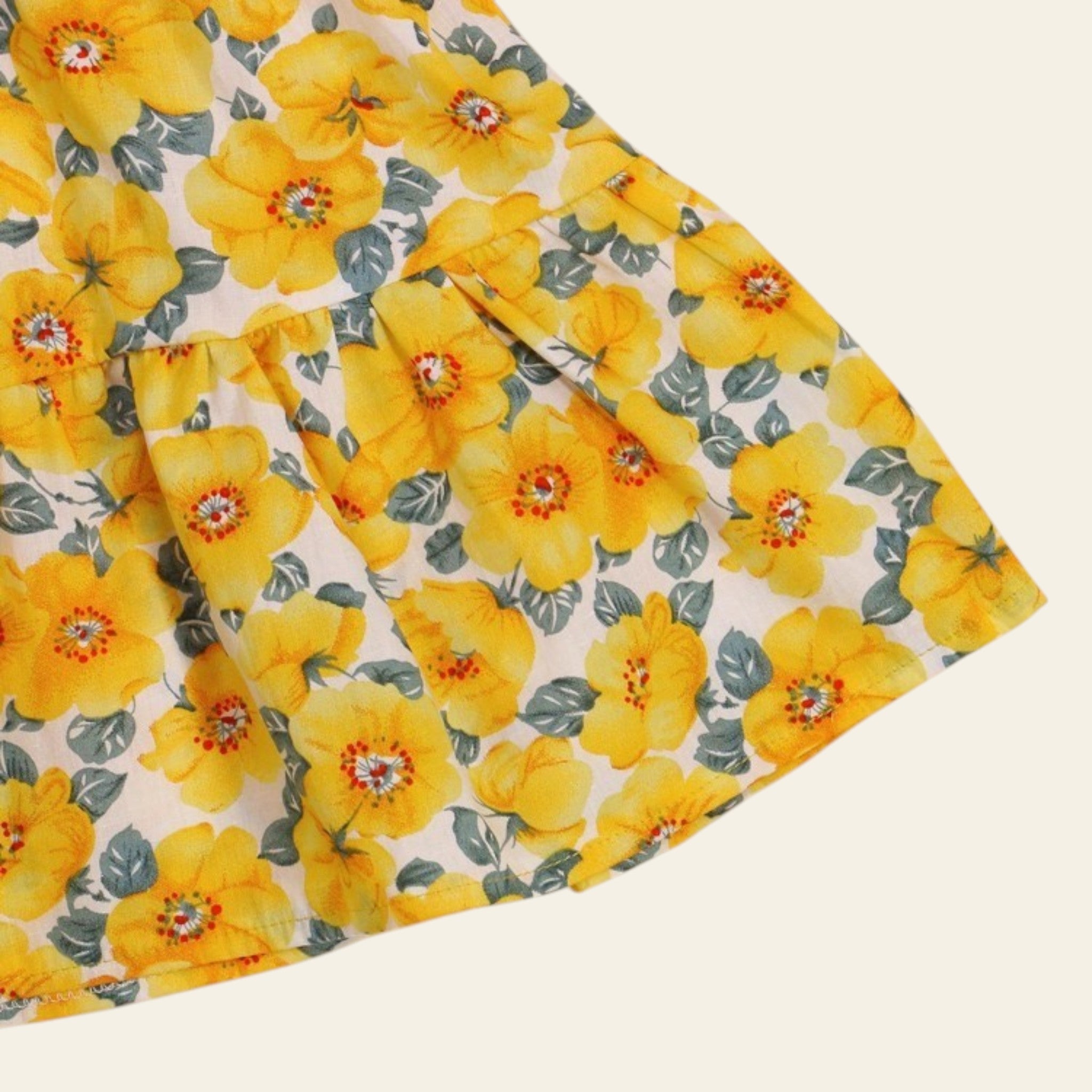 Floral fabric with yellow flowers and green leaves on a beige background