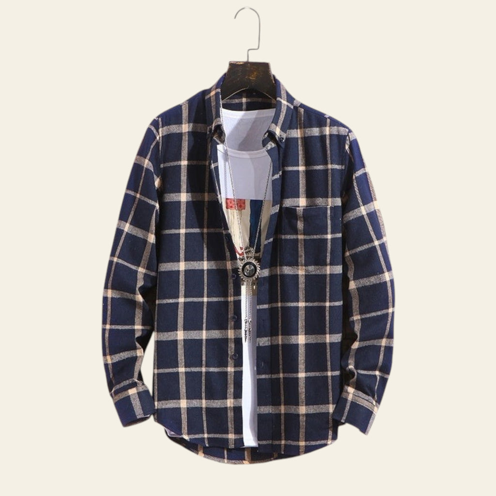 Blue plaid men's long sleeve shirt on hanger against brick wall