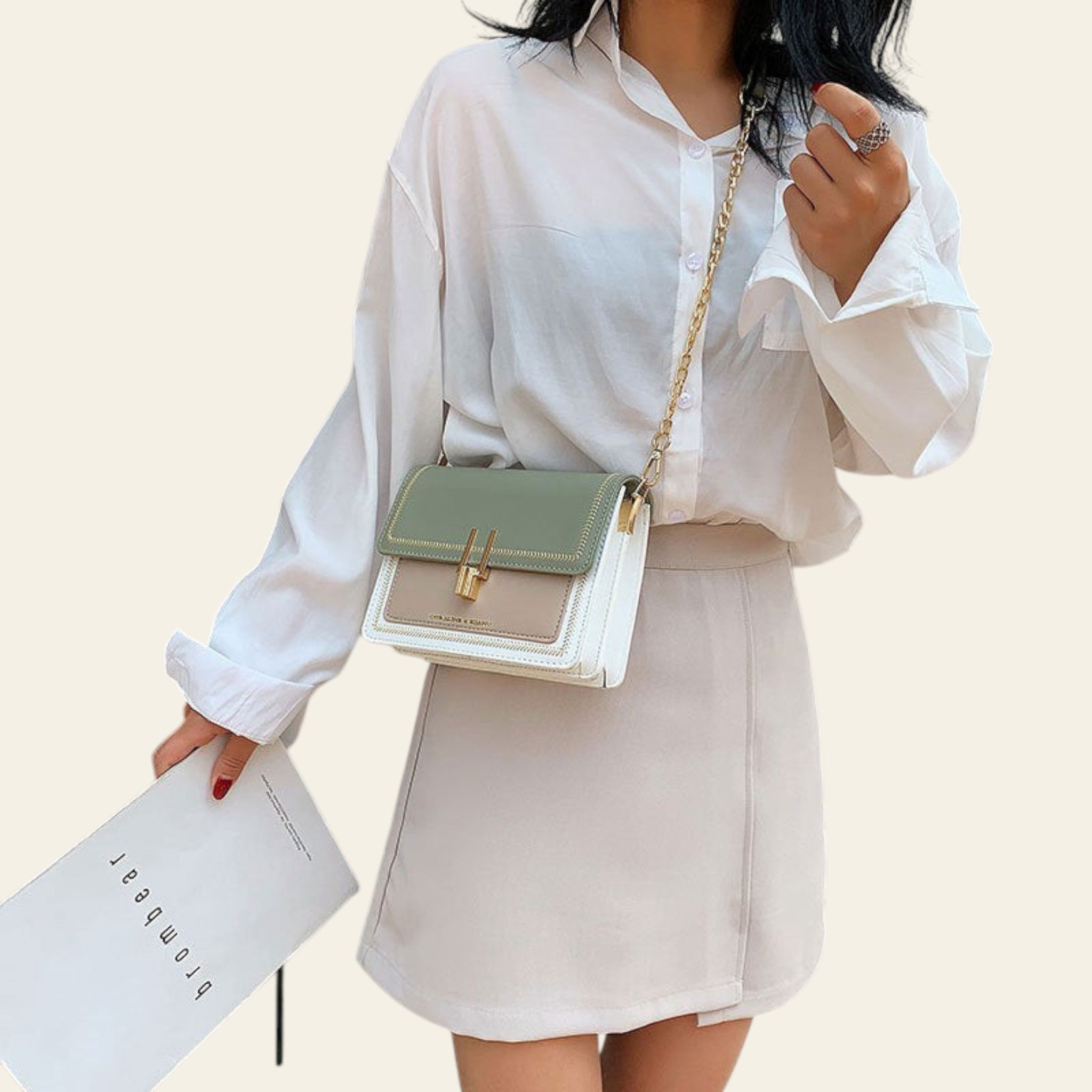 Person wearing a white shirt and holding a green handbag with a neutral bag underneath.