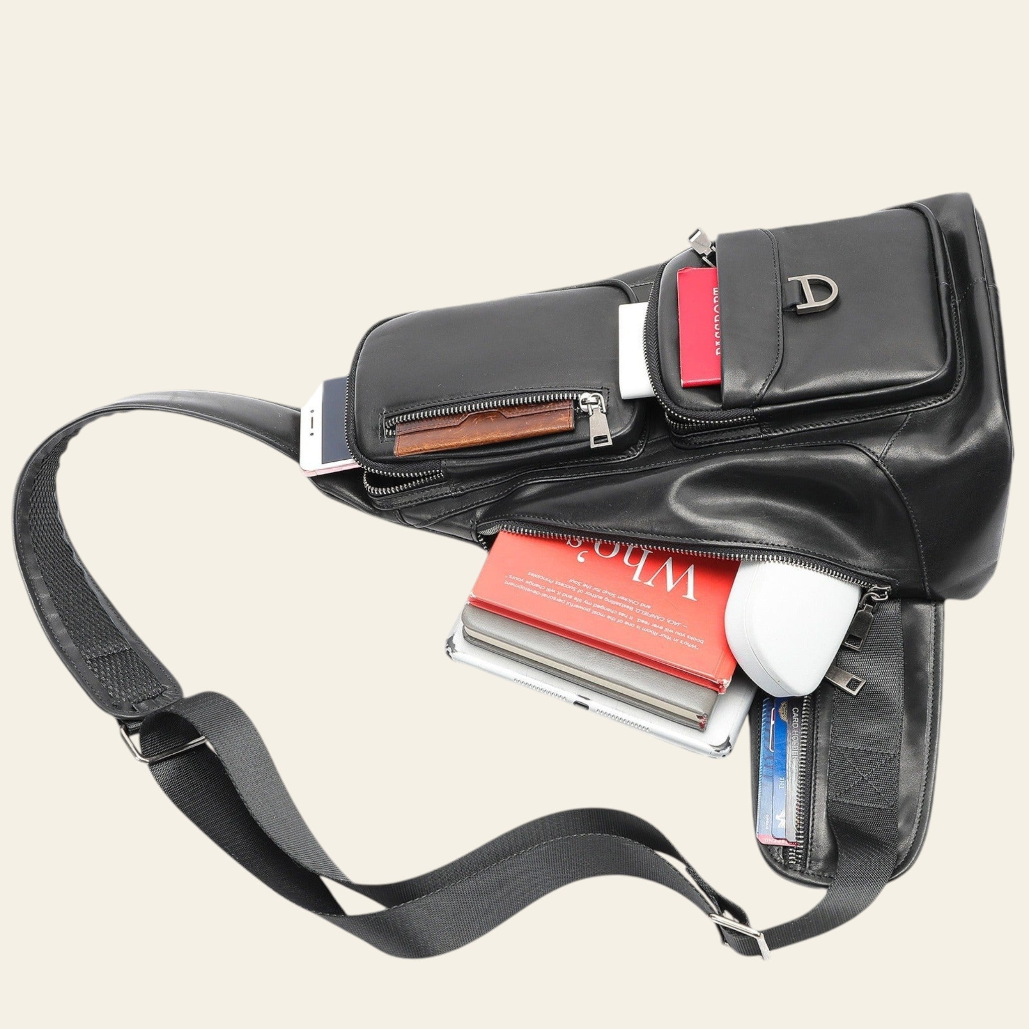 Black leather crossbody bag with compartments and a strap on a white background