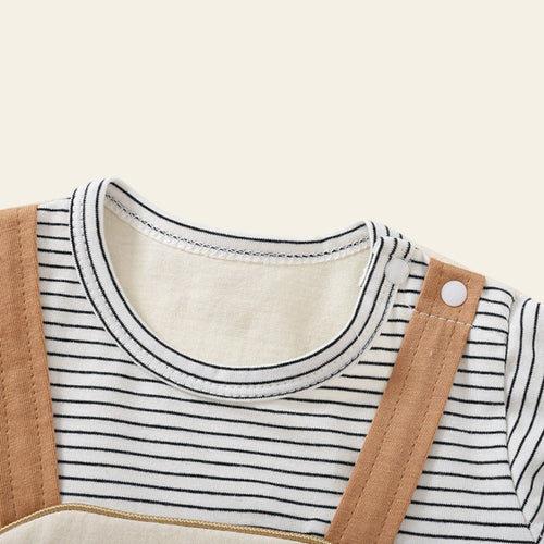 Close-up of a child's outfit with a striped shirt and brown overalls on a light gray background