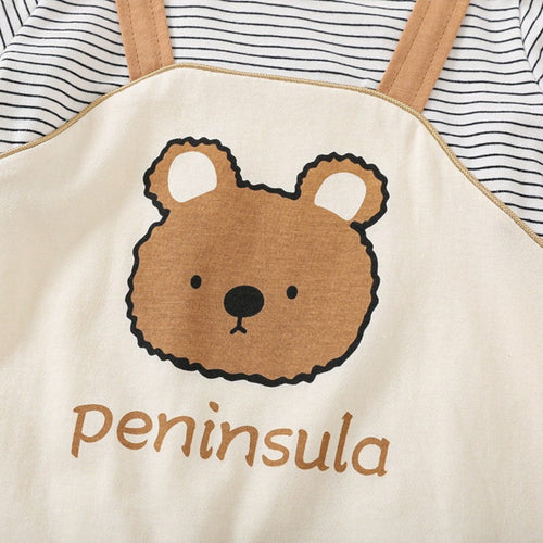 Beige apron with bear design and 'peninsula' text, worn over a striped shirt.